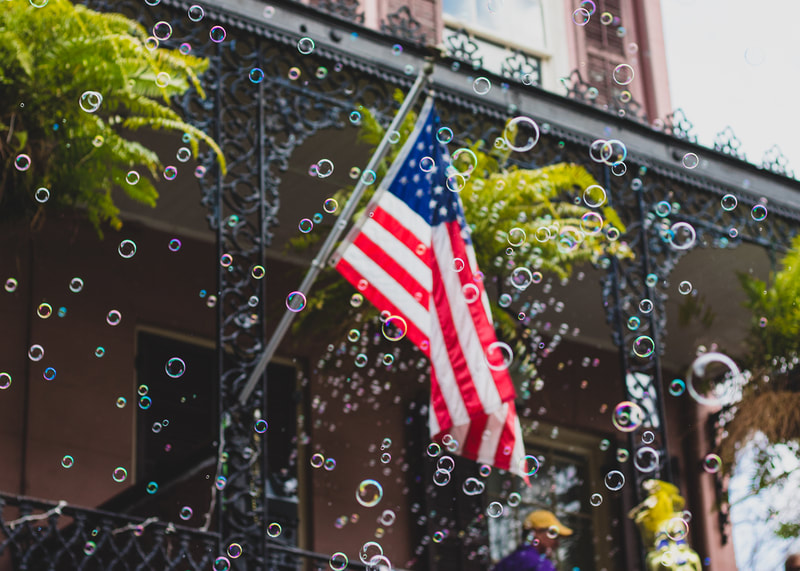 A colorful photograph of an American Flag surrounded by floating bubbles in New Orleans iconic French Quarter neighborhood.